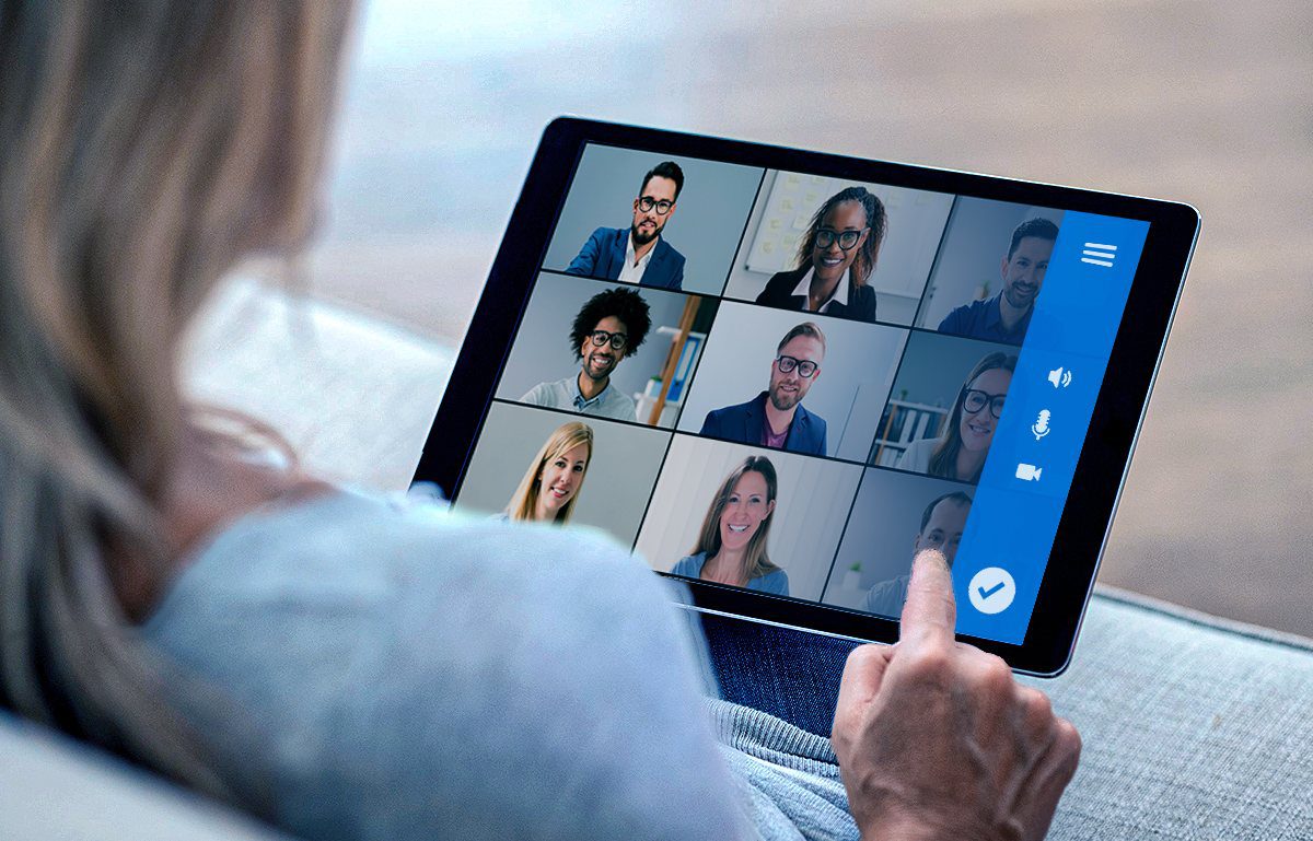 Uma mulher com um tablet na mão participando de uma reunião on-line