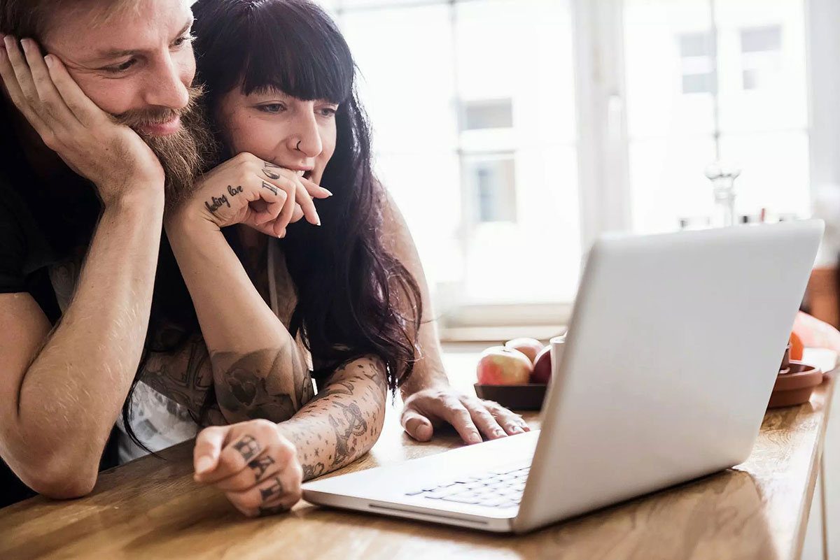Homem e mulher tatuados olhando para um notebook